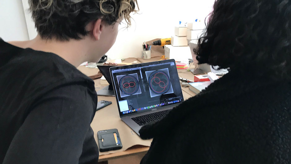 two people overlooking laptop with spirograph art